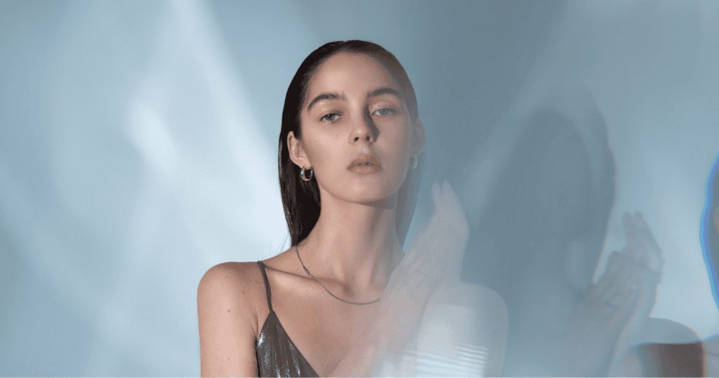 A woman gazes calmly forward through soft prisms of light with an unbothered, serene expression, embodying the tranquil clarity of someone completely detached from external turbulence.