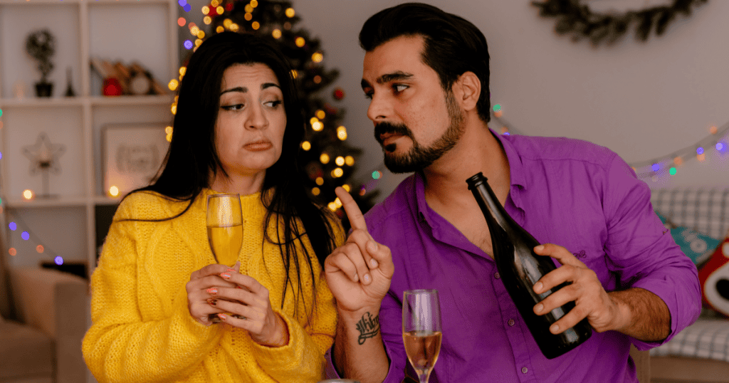 A man raises a warning finger at his doubtful partner during a holiday celebration at home, reflecting how a narcissist sets the rules about who you can meet and keeps you outside their inner circle.
