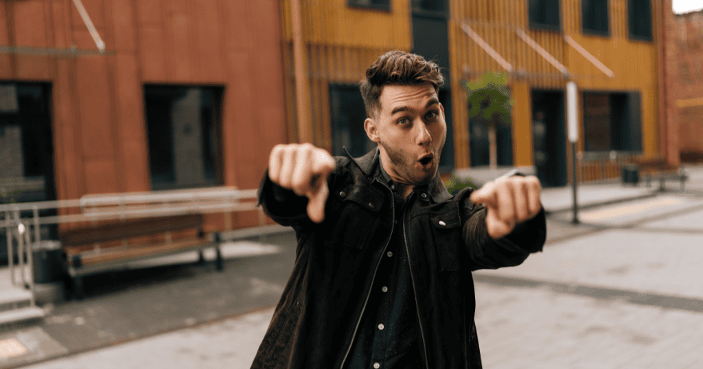 A man points both fingers forward with an exaggerated, playful expression, illustrating how a narcissist uses seemingly lighthearted moves to quietly check how much control they still have over you.