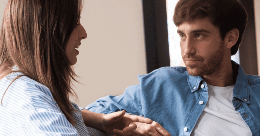 A man listens to a woman with a calm, calculating gaze as she opens up to him, illustrating how a narcissist quietly studies your words to find your weak spots in a single conversation.