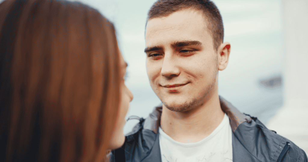 A young man gives a woman a knowing, sly smile as they talk face to face, reflecting how quickly a narcissist can size you up and pinpoint your weak spots.