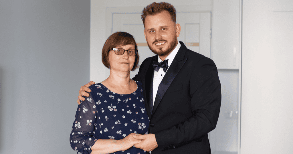 A mother holds hands with her smiling son in a tuxedo as they pose together, illustrating how a narcissistic family can cast one child as the hero who keeps up the family’s polished image.
