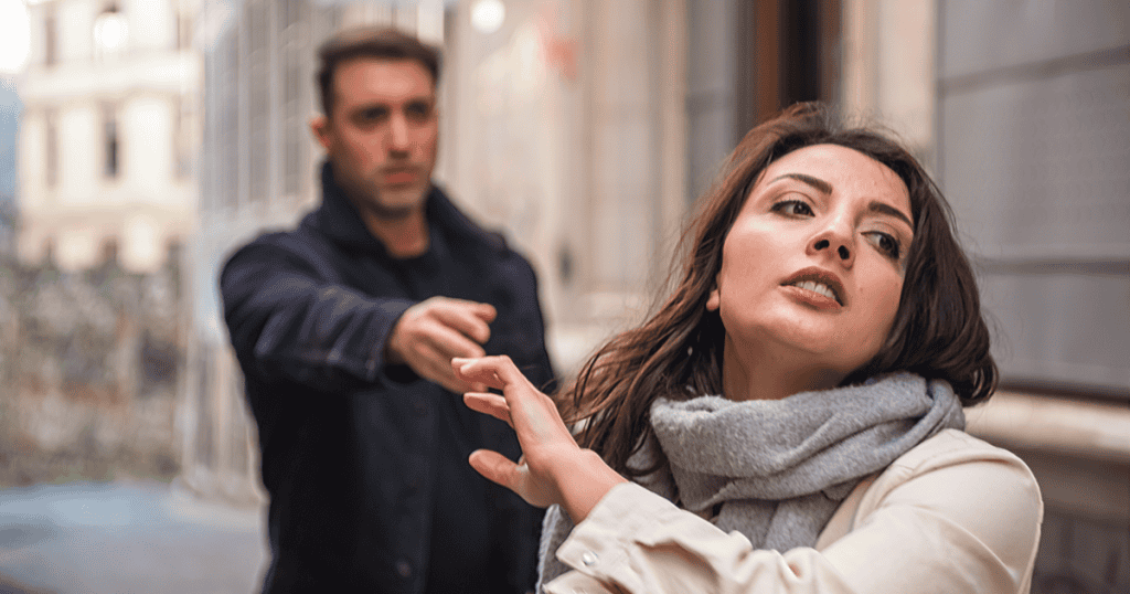 A woman turns away and raises her hand to stop a man reaching for her, capturing the moment a narcissist starts losing control as you refuse to keep chasing them.