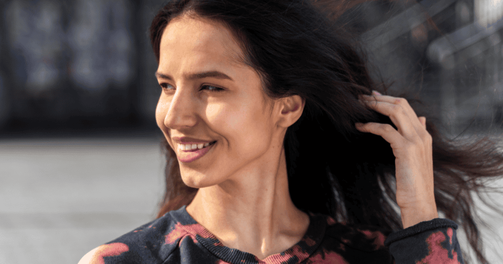 A woman smiles confidently as the wind sweeps through her hair, reflecting the strength of refusing to let a narcissist’s hurtful words define who you are.