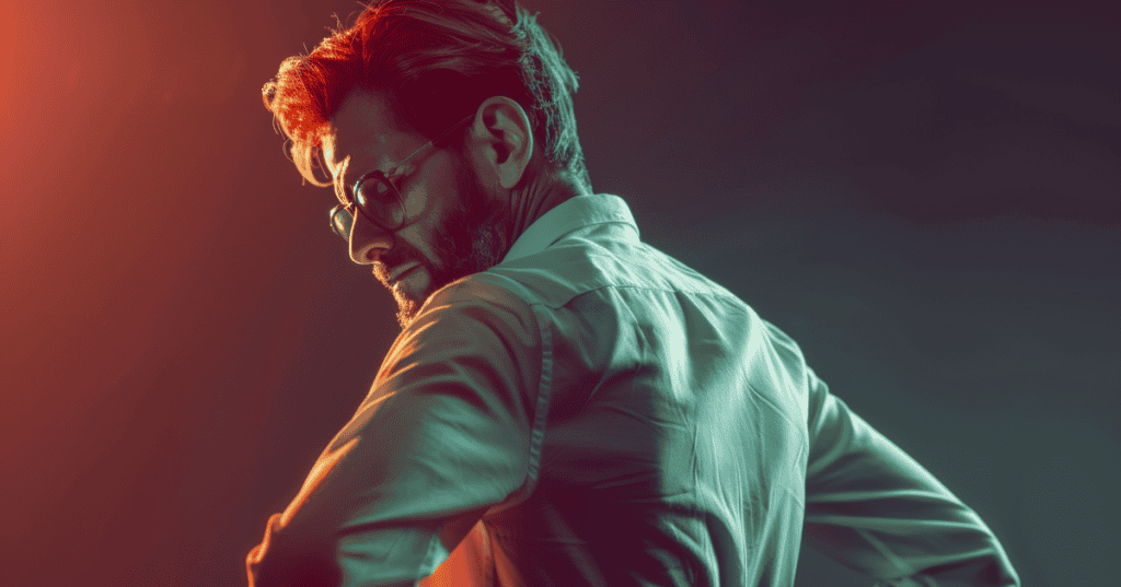A bearded man in glasses glances back over his shoulder with a cold, smug expression under dramatic red and teal lighting, capturing the sense of superiority a narcissist feels when your apology hands them more power.