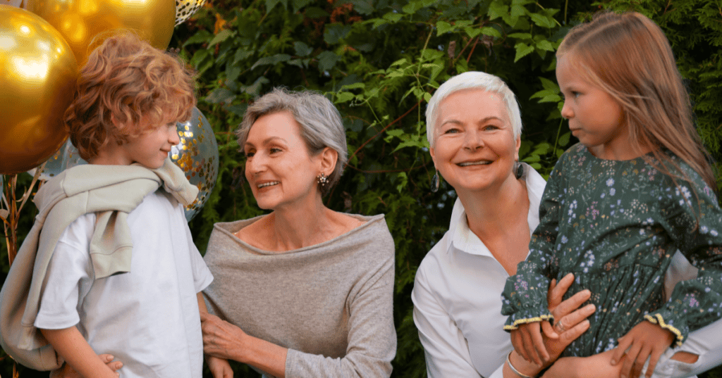 Two grandmothers smile warmly with their grandchildren at a balloon-filled celebration, illustrating how a narcissist’s kindness tends to show up most when there are others around to see it.
