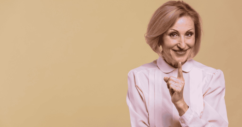 An older woman smiles smugly while raising a knowing finger, illustrating the false confidence of a narcissist who insists you can’t survive without them.