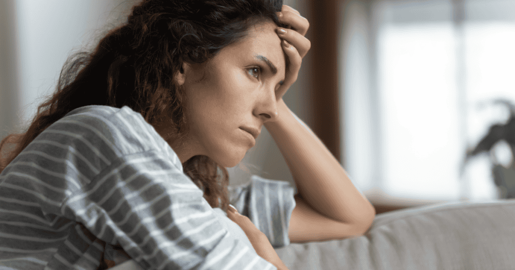 A woman rests her head in her hand and stares off with a weary, troubled expression, capturing the frustration of watching a narcissist twist your apology into evidence against you.