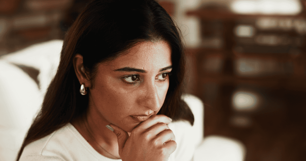 A woman stares into the distance with a troubled, worried expression, reflecting the confusion of being made dependent by a narcissistic parent and then shamed for needing them.