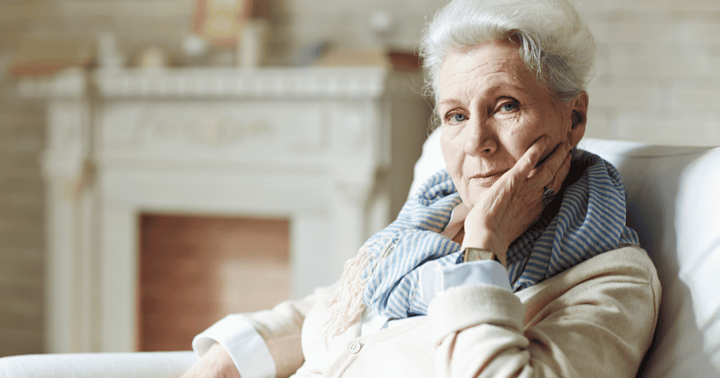 An elderly woman rests her cheek on her hand with a cool, appraising gaze, reflecting how a narcissistic parent sees their child as something they own rather than someone they love.