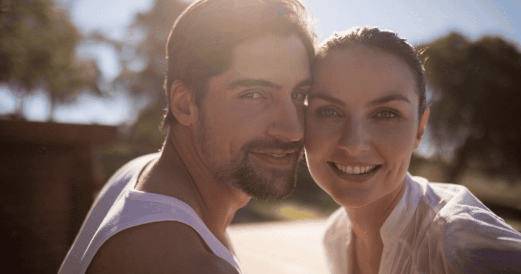 A smiling couple leans in cheek to cheek in warm sunlight, showing the healthy, genuine love that becomes possible once you recognize the pattern that kept drawing you to narcissists.