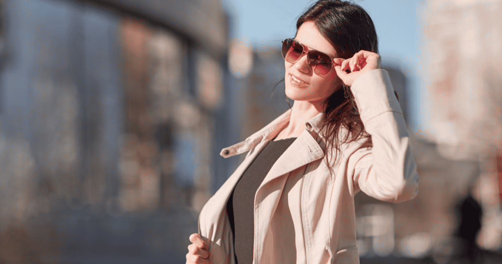 A confident woman in sunglasses smiles in the city sunlight, reflecting the freedom of realizing you were never meant to belong to a narcissistic parent, only to yourself.